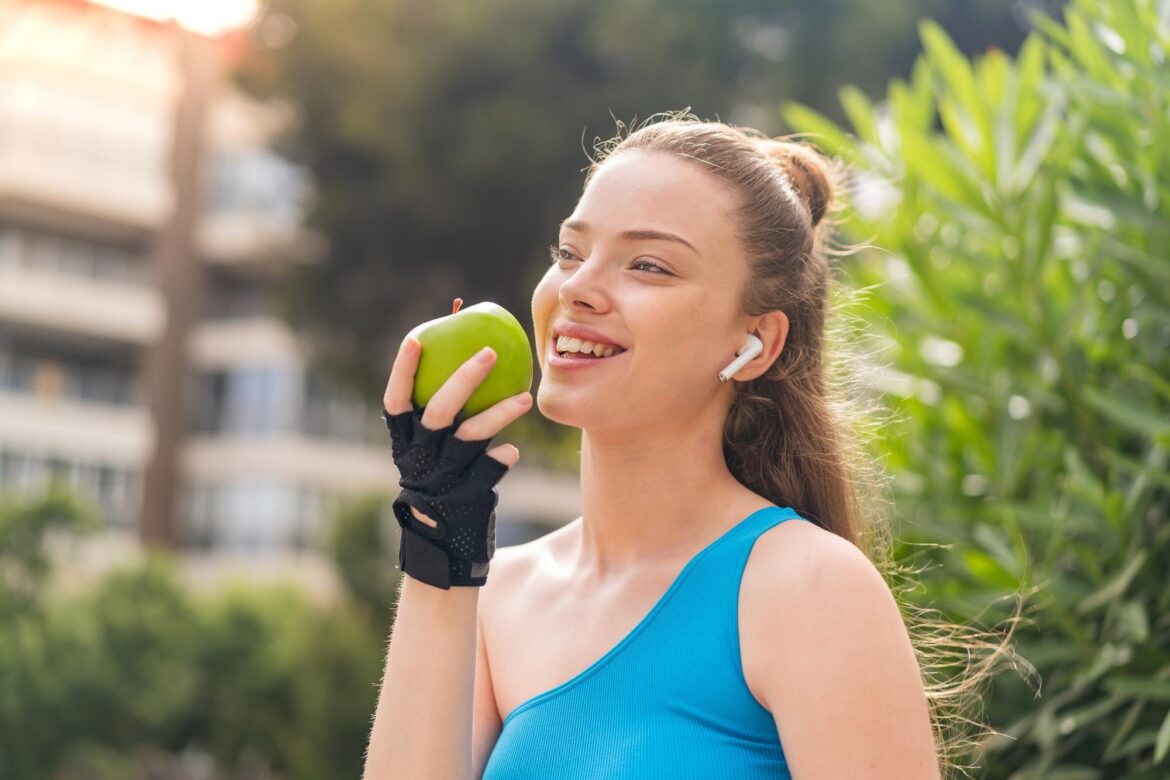 Egy egészséges mosolyú nő almát eszik.